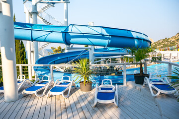 Water Slide Pool Loungers; Relaxing by the pool with a water slide at a water park.