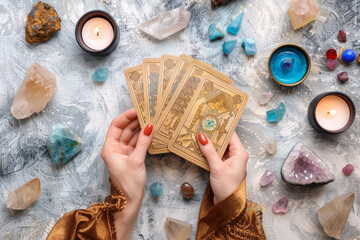 woman hands holding tarot cards, fortune telling, prophecy reading concept, top view esoteric magical layout with crystals, oracle and candles