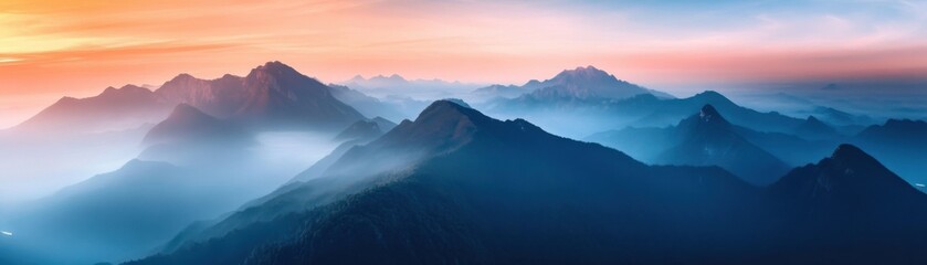 Fototapeta premium Dramatic mountain peaks bathed in sunset, with misty valleys and a vibrant orange to blue gradient sky.