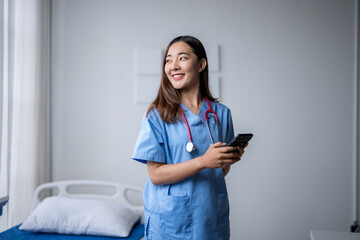 Happy young nurse using smartphone in hospital room