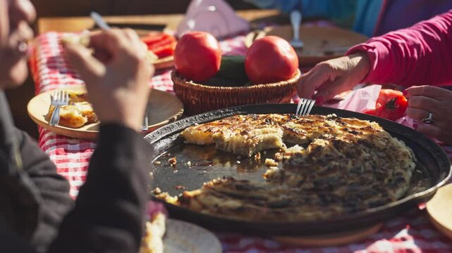 Close-up of a Traditional Turkish and Balkan Dish Borek Being Eaten From a Baking Pan Placed by a Basket of Vegetables. The dish contain meat filling wrapped in flaky filo pastry