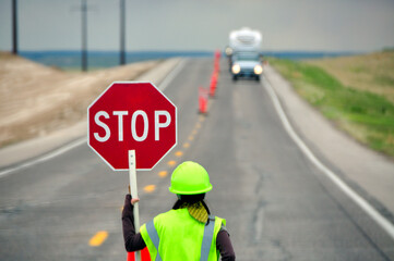 Highway flagman flagwoman stops oncoming highway traffic construction stop sign