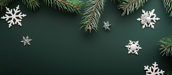 Minimalist winter and new year composition featuring white snowflakes and a Christmas tree branch on a green backdrop, ideal for your mockup with a flat lay, top view, and ample copy space image.