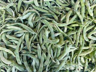 Green beans vegetable, top view background. Large amount of green beans in pods on market stall. Fresh green beans at farmers market in Greece. Healthy, vegetarian food.