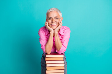 Photo of nice aged woman pile stack book empty space wear pink shirt isolated on teal color...