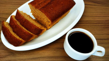 Cinnamon cake, some slices and cup of coffee on the wooden table
