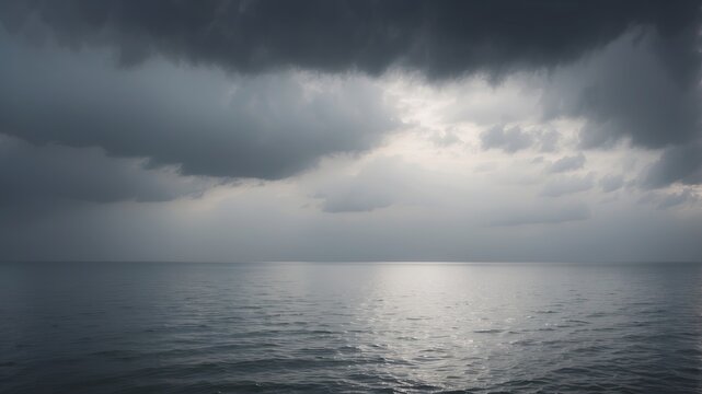 A vast, grey sky with clouds rolling over a calm, tranquil sea The horizon is lost in the mist.