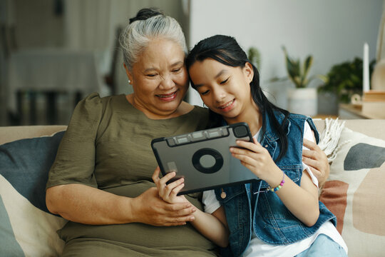 Granddaughter watching video on digital tablet together with her grandmother at home