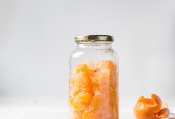 tangerine cheong in a glass jar on a white background, korean tangerine cheong in a transparent jar, tangerine in sugar syrup, process of making tangerine cheong