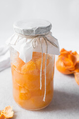 tangerine cheong in a glass jar on a white background, korean tangerine cheong in a transparent jar, tangerine in sugar syrup, process of making tangerine cheong