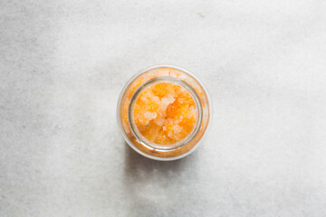 Overhead view of tangerine cheong in a glass jar on a white background, top view of korean tangerine cheong in a transparent jar, tangerine in sugar syrup, process of making tangerine cheong