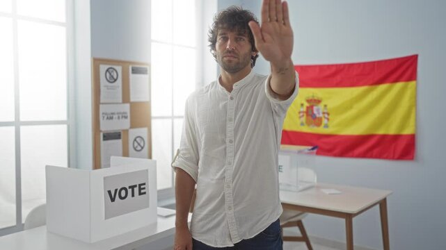 Young hispanic man wearing shirt standing with serious expression, stop hand gesture in confident defense at spanish electoral college