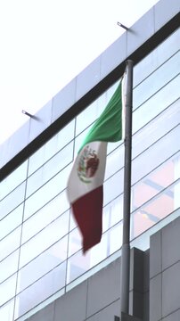 Bandera de M&eacute;xico ondeando con edificios atr&aacute;s