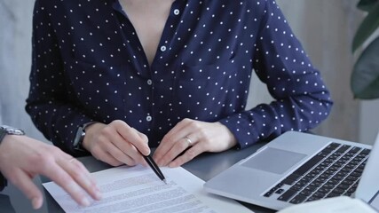 Detailed view of two business people or lawyers signing a contract with a laptop nearby