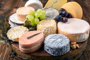 Traditional cheese platter with soft cheese and fruits served as close-up on a rustic wooden design...