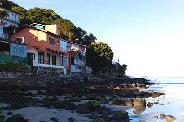 Colorful hillside village by the beach, surrounded by lush greenery and calm ocean waves