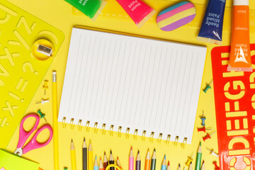 Back to school concept with variety of office and school supplies on yellow background.	