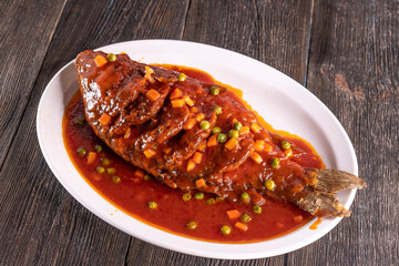 fried fish in sweet and sour sauce on wood table. Chinese food. food concept.