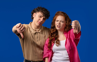 Naklejka premium Young couple with sign of dislike. Shaming man and woman, thumbs-down, dont like