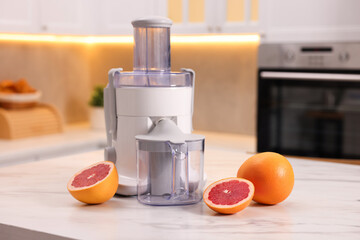 Modern juicer and fresh grapefruits on white marble table in kitchen