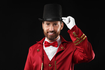 Portrait of showman in red costume and hat on black background