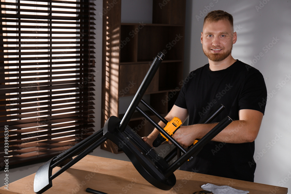 Poster Man with electric screwdriver assembling chair in room