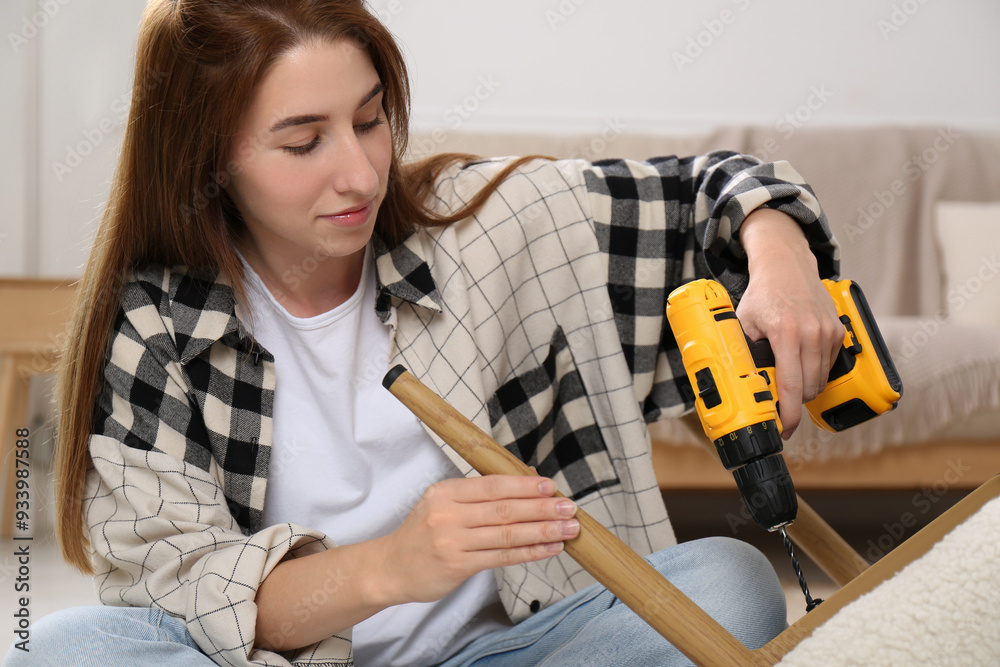 Canvas Prints Woman with electric screwdriver assembling armchair at home