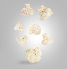 Delicious khinkali (Georgian dumplings) falling on grey gradient background