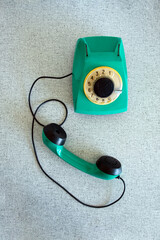 Green rotary telephone set on a gray table. Retro style, vintage. Vertical photo