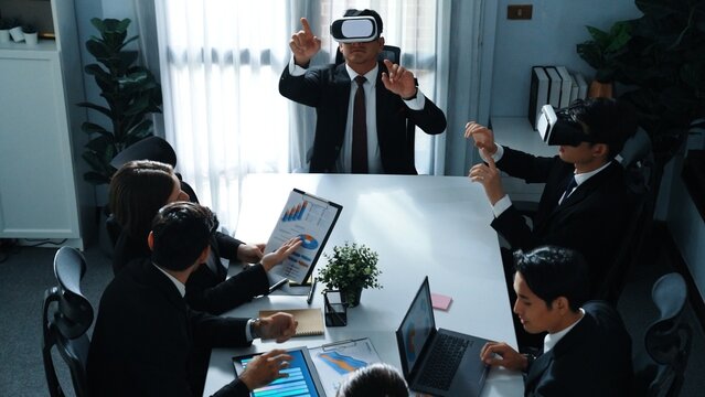 Top view of manager working on laptop and sending data analysis to business people by using VR glass headset while diverse team planning marketing strategy and looking at financial graph. Directorate.
