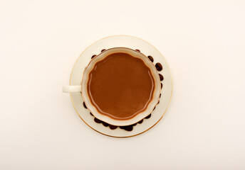 A white cup of coffee and scattered coffee beans.
