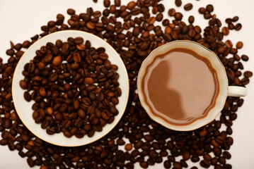 A white cup of coffee and scattered coffee beans.