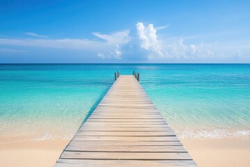 Obraz premium A serene pier stretches into the clear turquoise ocean under a bright blue sky with scattered clouds.