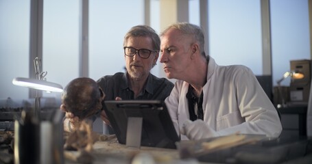 Two archaeologists examine fossil skull, conduct historical and scientific research on remains of...