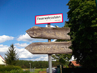 Wegweiser in einem Dorf mit Aufschrift - Feuerwehrzufahrt - Bau Mensch Natur und Naturfarbe Atelier