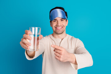 Portrait of nice young man point finger water glass wear pajama isolated on blue color background