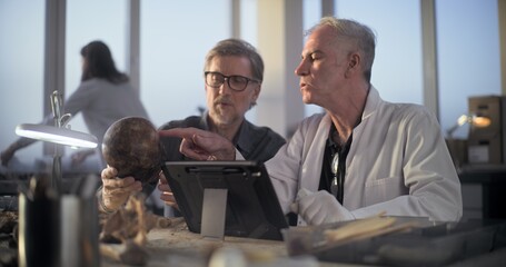 Two archaeologists examine fossil skull, conduct historical and scientific research on remains of...