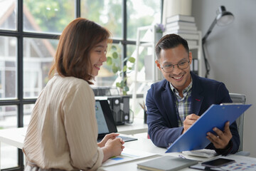 Businessman holding clipboard and smiling while having a meeting with his colleague at the office