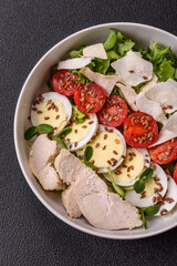 Delicious fresh caesar salad in a bowl with chicken breast, egg, tomatoes
