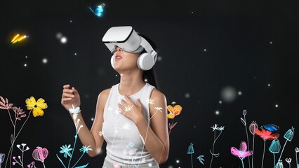 Beautiful Asian woman with VR to metaverse interacting virtual neon flowers, pointing while talking to butterfly with new neon blossom in 3D pollen graphic floating meta garden world. Hallucination.