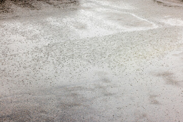 Rainy summer day on asphalt with puddles and droplets creating bubbles.