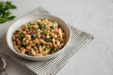 Homemade White Bean Salad with Herbs and Onion in a Bowl, side view. Copy space.