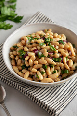Homemade White Bean Salad with Herbs and Onion in a Bowl, side view.
