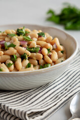Homemade White Bean Salad with Herbs and Onion in a Bowl, side view. Close-up.