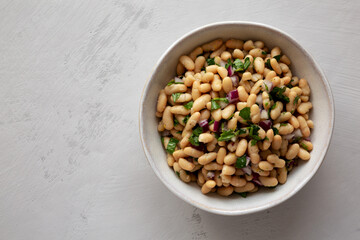 Homemade White Bean Salad with Herbs and Onion in a Bowl, top view. Flat lay, overhead, from above.