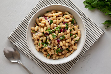 Homemade White Bean Salad with Herbs and Onion in a Bowl, top view. Flat lay, overhead, from above.