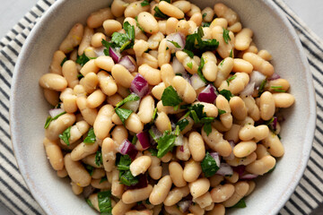 Homemade White Bean Salad with Herbs and Onion in a Bowl, top view. Flat lay, overhead, from above.