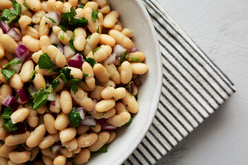 Homemade White Bean Salad with Herbs and Onion in a Bowl, top view. Flat lay, overhead, from above.