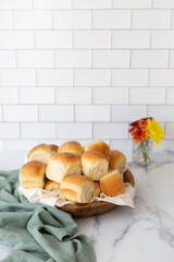 Freshly Baked Dinner Rolls in a Wooden Bowl on a White Countertop with White Tile Background