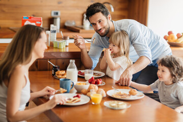 Happy family enjoying breakfast together in cozy kitchen